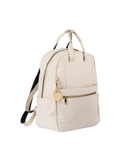 An off-white canvas backpack with gold-tone hardware, featuring a front zippered pocket with a decorative gold heart charm, top carry handles, and a black adjustable shoulder strap, shown on a plain white background.