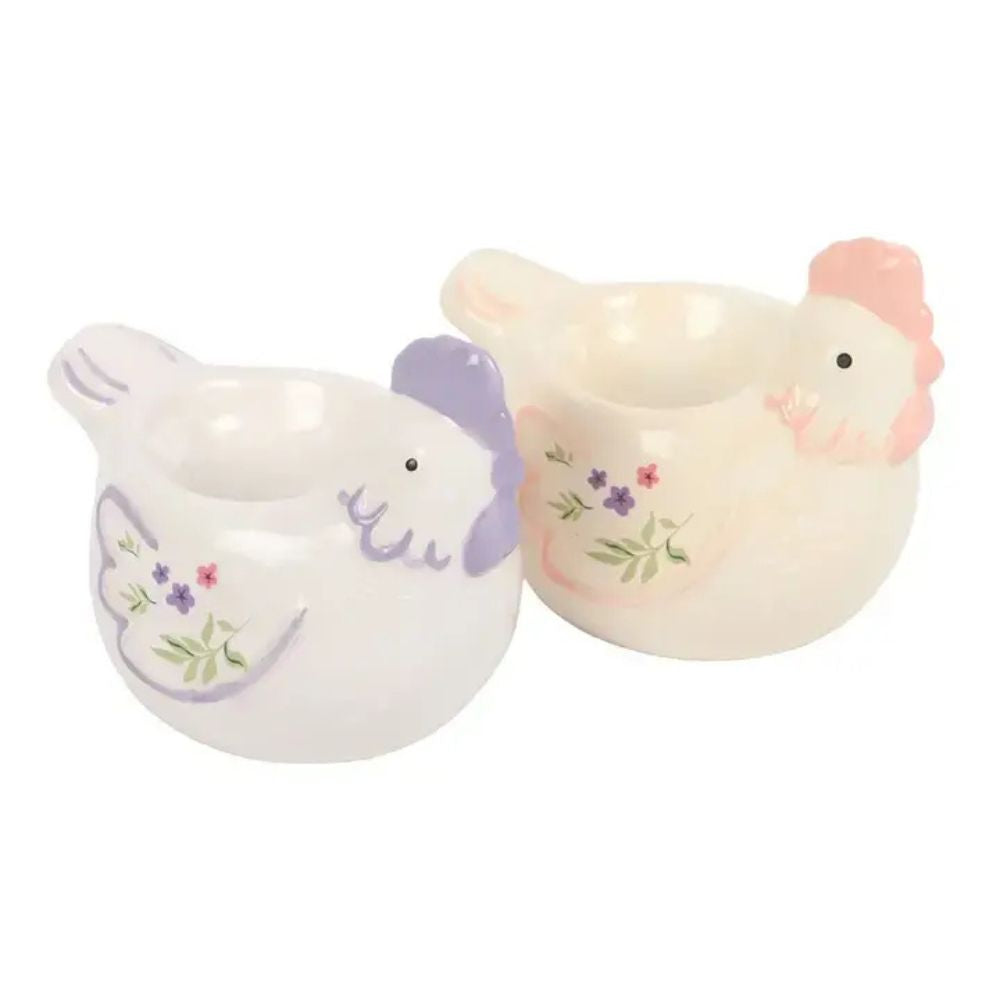 Two ceramic chicken-shaped egg cups with decorative floral designs on a white background