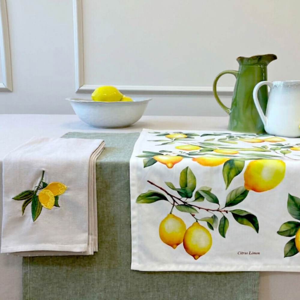 Kitchen setting with lemon-themed tablecloth, napkins, and pitcher on a countertop.
