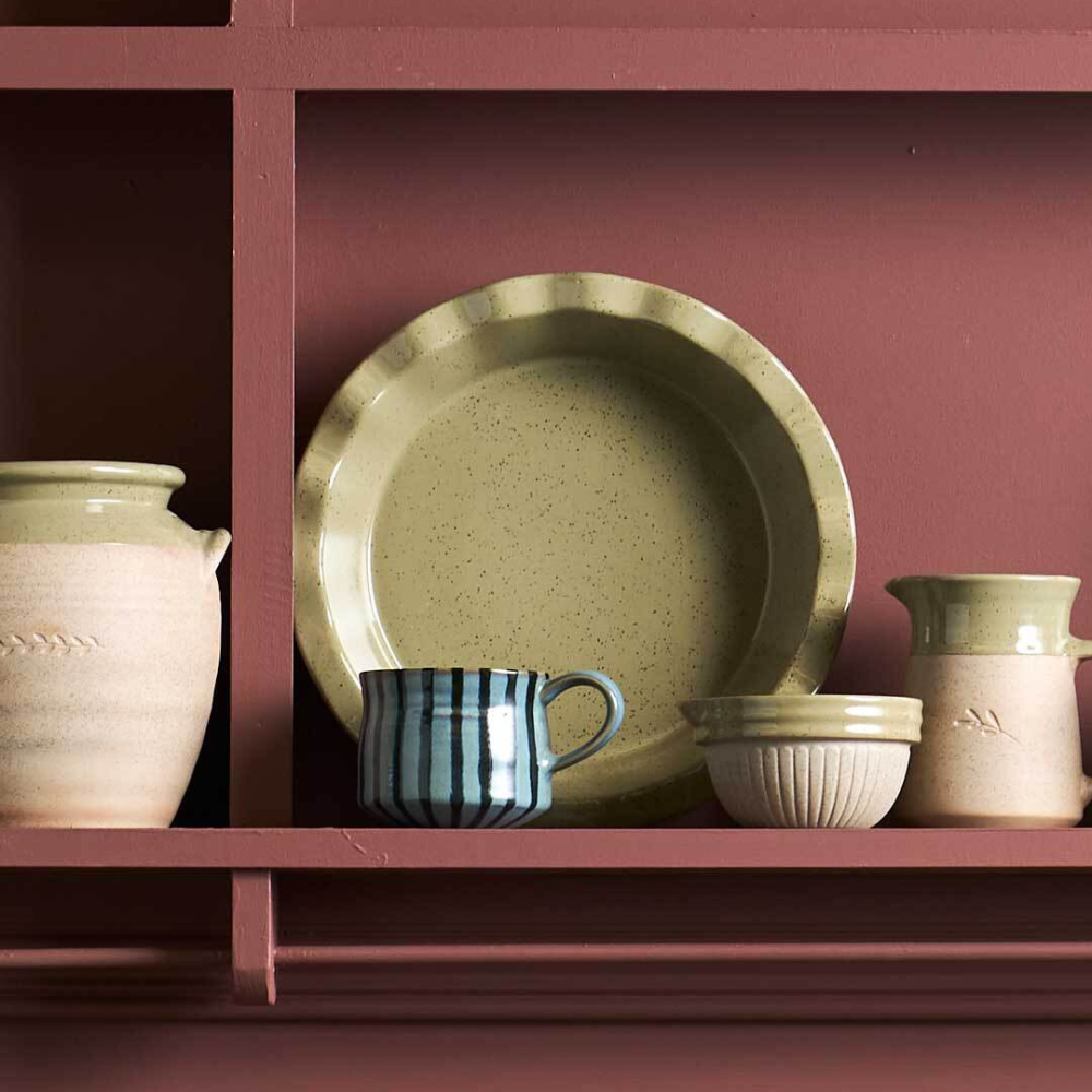 Set of ceramic dishes on a pink shelf against a pink wall