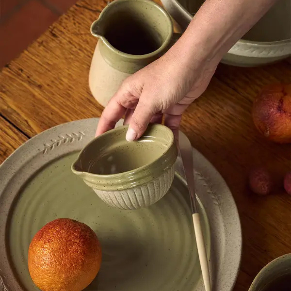 Person using a ceramic juicer on an orange with a wooden table background