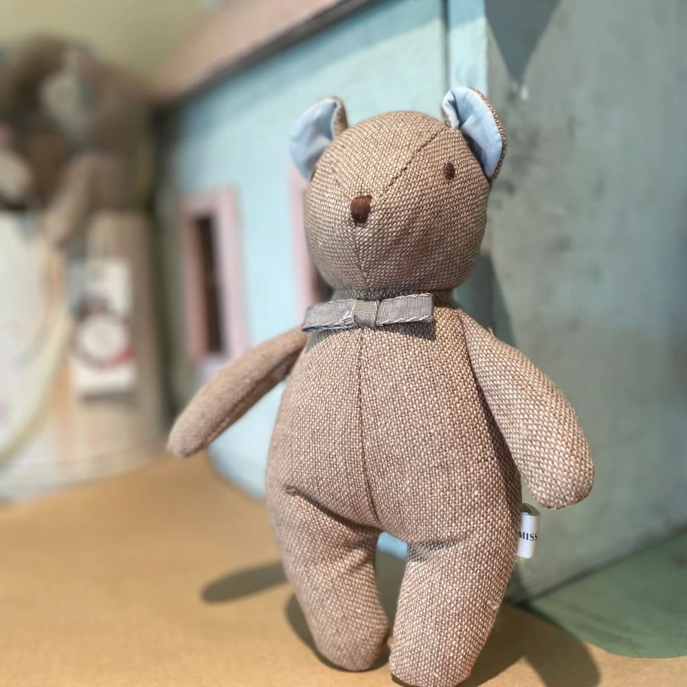 Textured teddy bear with a bow tie on a surface with a blurred background
