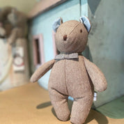 Textured teddy bear with a bow tie on a surface with a blurred background