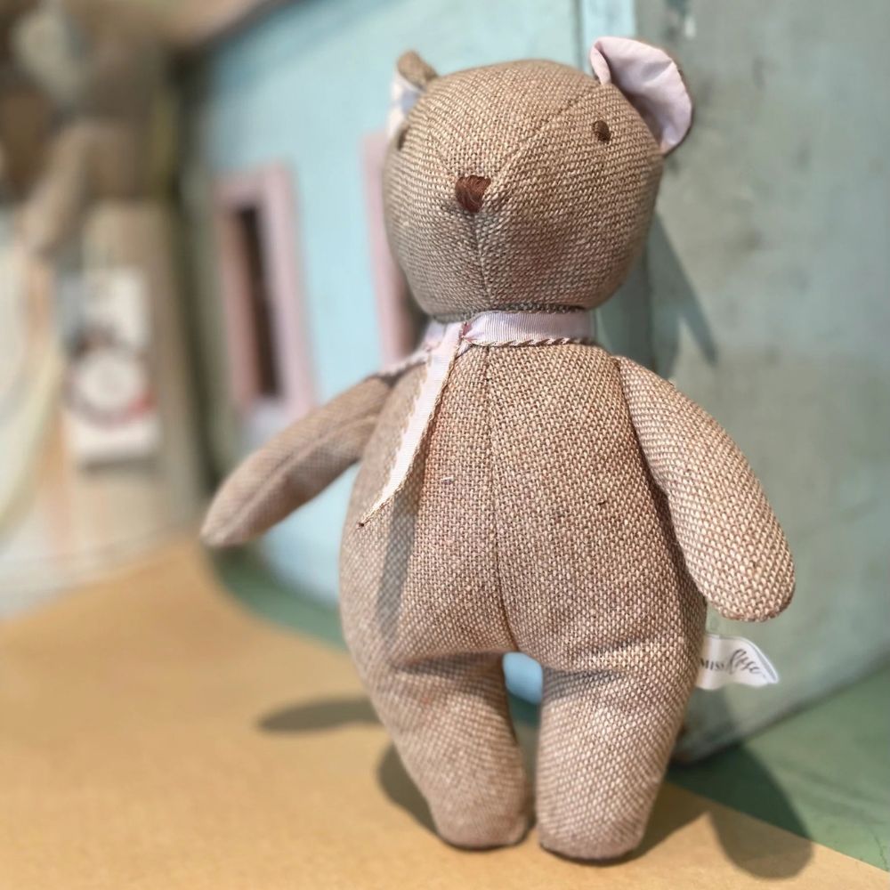 Textured teddy bear on a wooden surface with a blurred background
