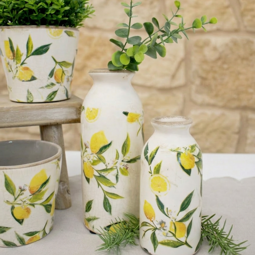 Decorative vases with lemon and leaf patterns on a stone surface.