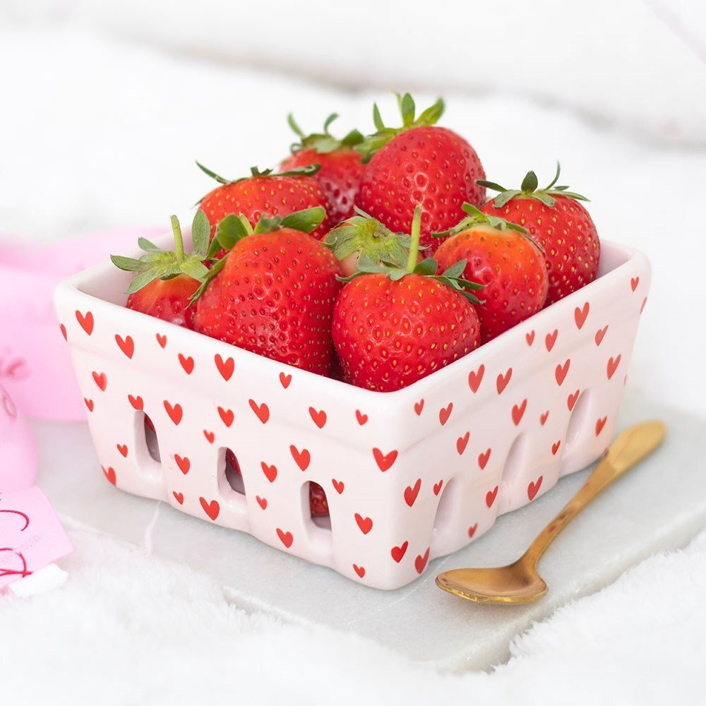 Pink ceramic basket with red heart patterns filled with strawberries