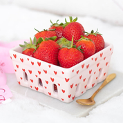Pink ceramic basket with red heart patterns filled with strawberries